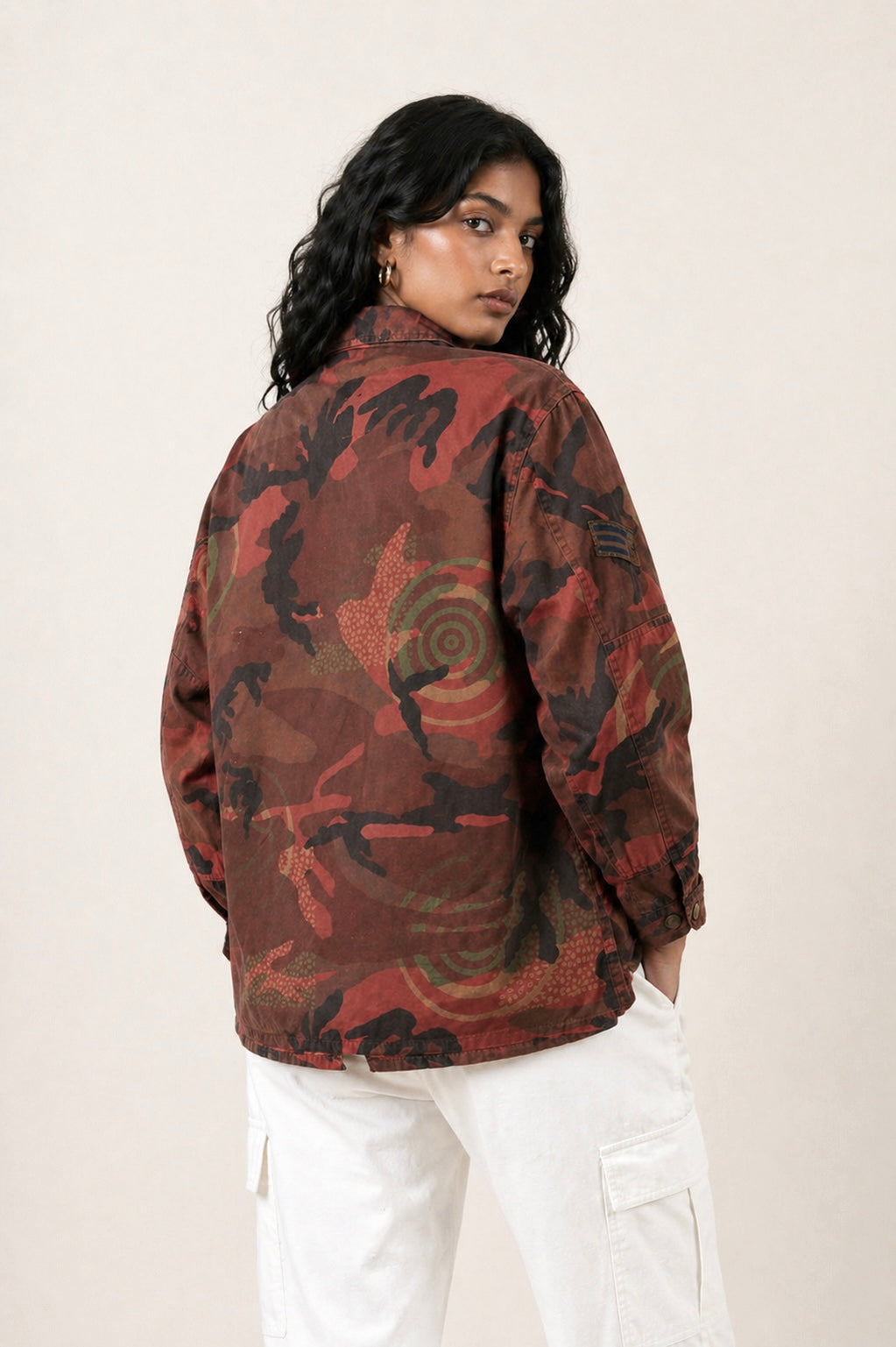 Exclusive reworked military jacket featuring earthy rust dye, subtle geometric patterning, and artisan mirror embroidery