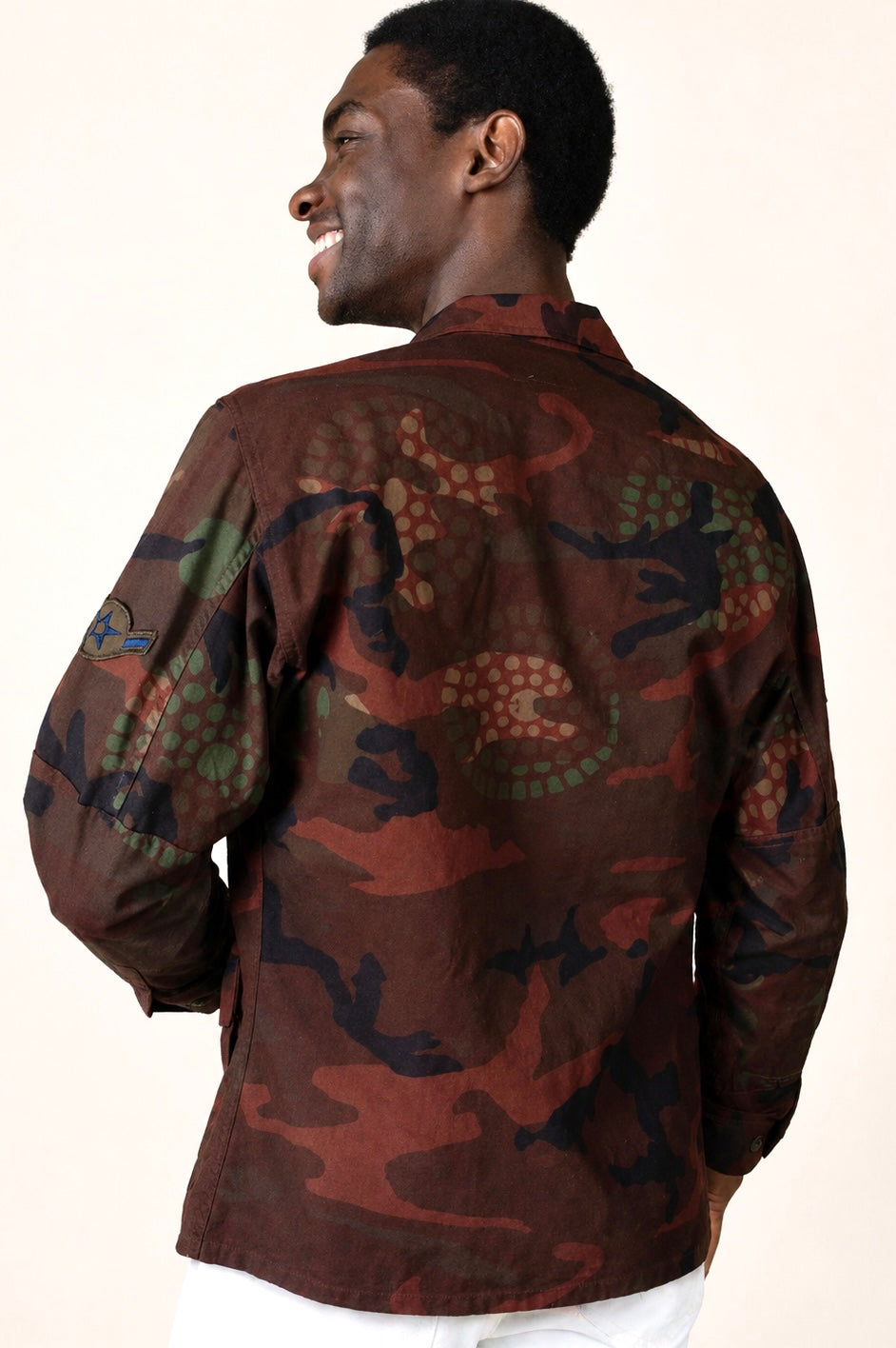 Exclusive reworked military jacket featuring earthy rust dye, subtle geometric patterning, and artisan mirror embroidery