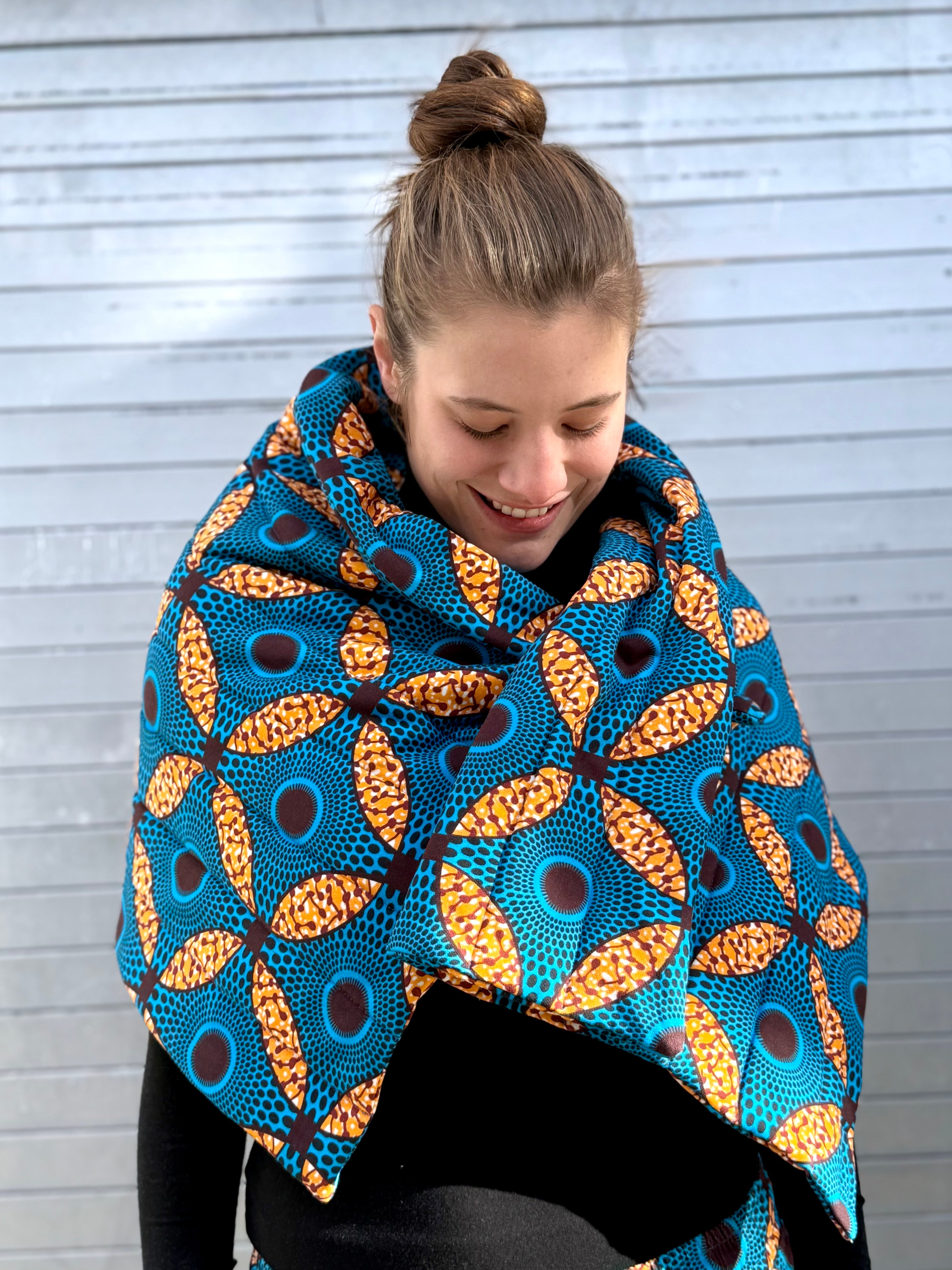 Model wearing the Ìmọ́lẹ̀ Padded Sweat Scarf in blue, a quilted organic cotton scarf with Yoruba-inspired print by Lola Faturoti Loves. Handcrafted in organic cotton, made for warmth, comfort, and radiant self-expression.